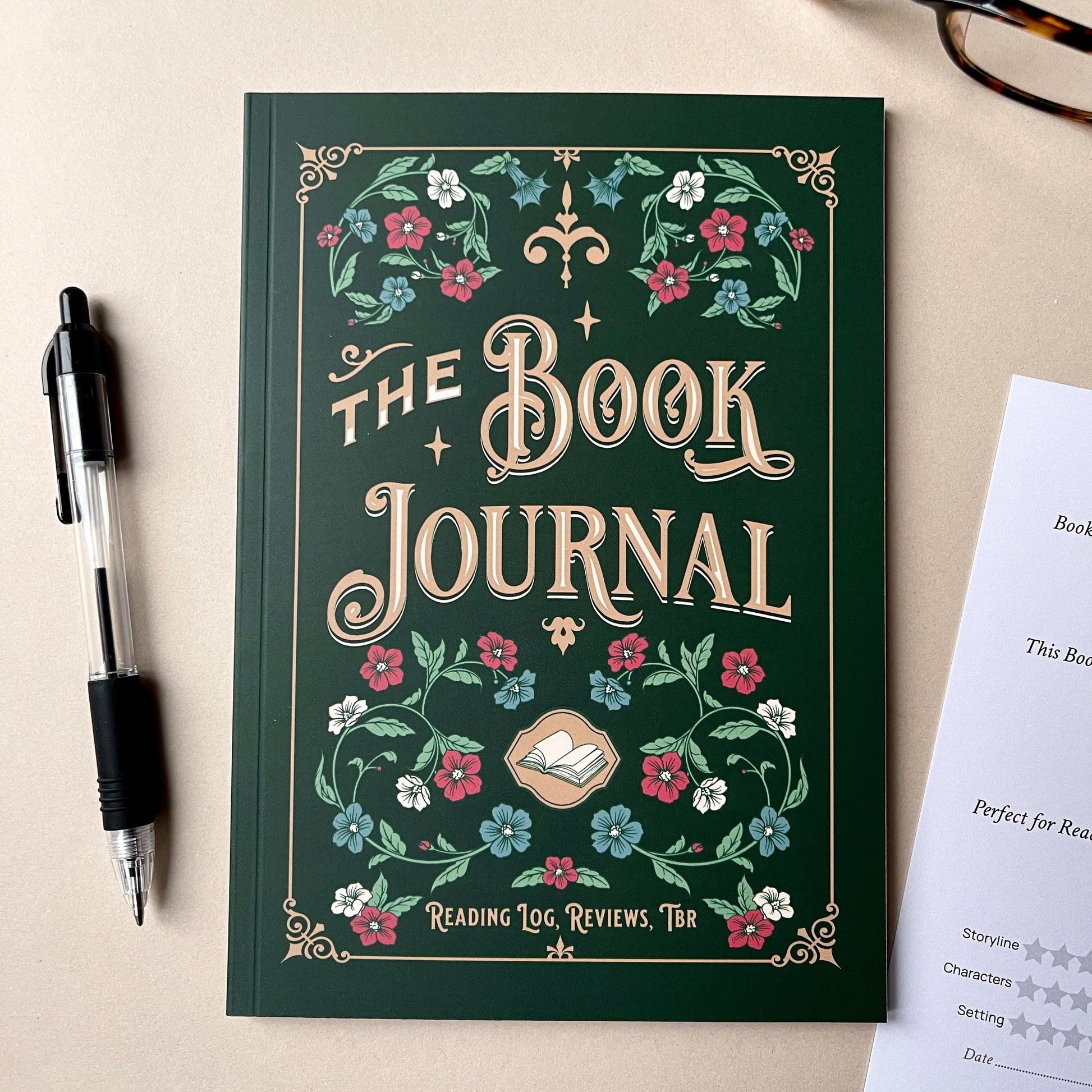 Book Journal with floral design on a beige surface with a pen and paper.